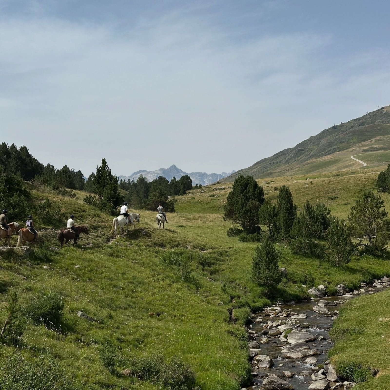 Grupo de jinetes junto a un río de montaña en el valle de Aran